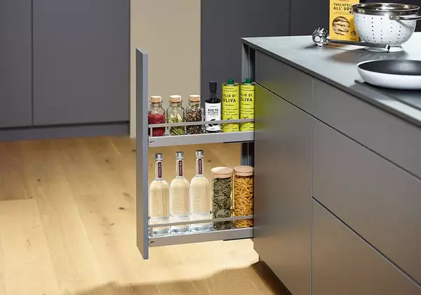 Moderner Küchenauszug mit Gewürzen, Ölflaschen und Pasta auf hellem Holzfußboden.