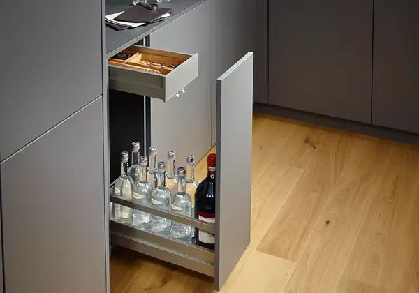 Moderner Küchenschrank mit Auszug für Flaschen und Schublade für Besteck auf Holzfußboden.